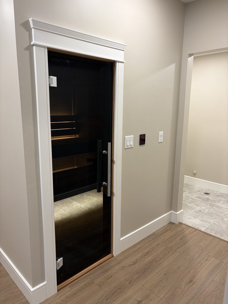 Built-in Ambara sauna exterior with tinted glass door and wall-mounted temperature control