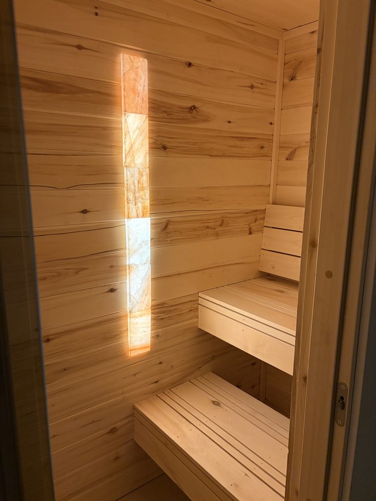 Aspen sauna interior with glowing Himalayan salt brick light column and tiered benches